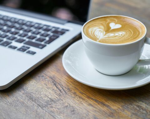 Stockfoto. Computer met een kopje koffie met latte art