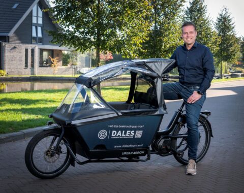 Jorn, eigenaar van Dales Finance, zit lachend op het zadel van een bakfiets. Op de bakfiets staat de tekst: ‘Heb jij je boekhouding op orde? Dales Administratiekantoor.’ De foto straalt toegankelijkheid en deskundigheid uit.
